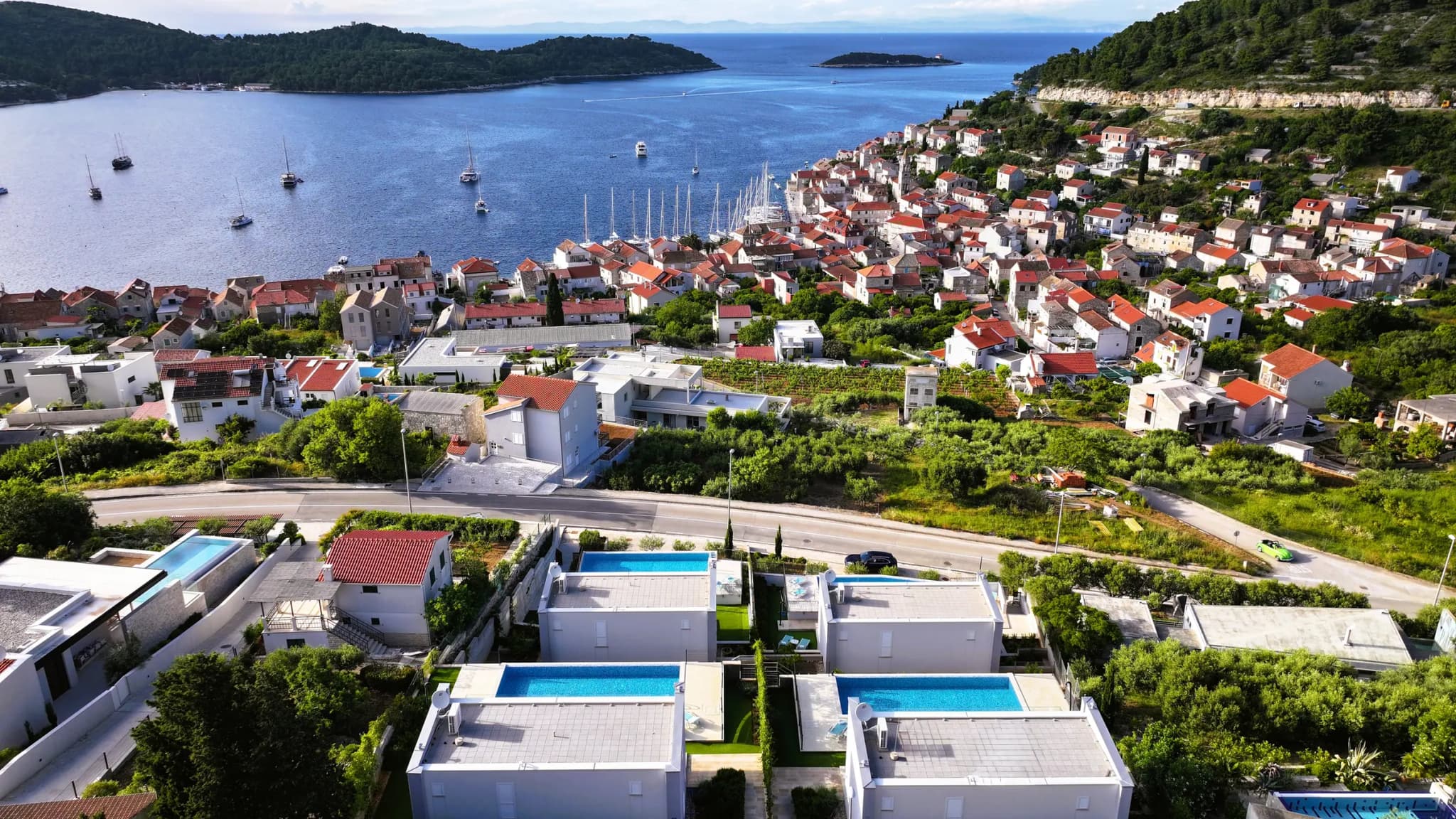 Die vier Blue Villas aus der Luft, mit Pools, der Stadt Vis und der Bucht dahinter