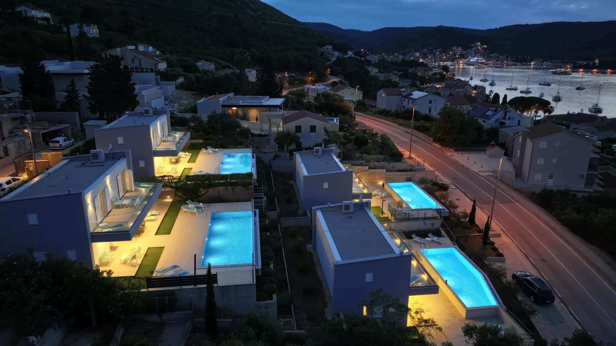 Die vier Blue Villas nachts aus der Luft, beleuchtete Pools und dahinter die Bucht von Vis